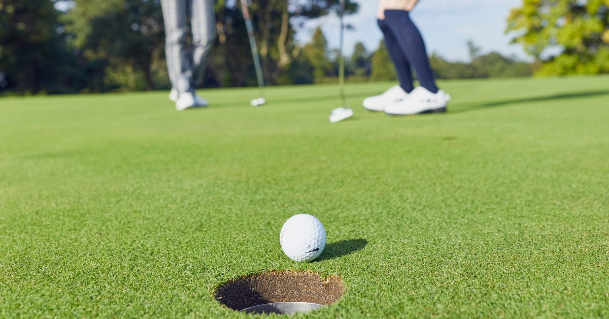 Golf Players on the Green with a Golf Ball Near the Hole