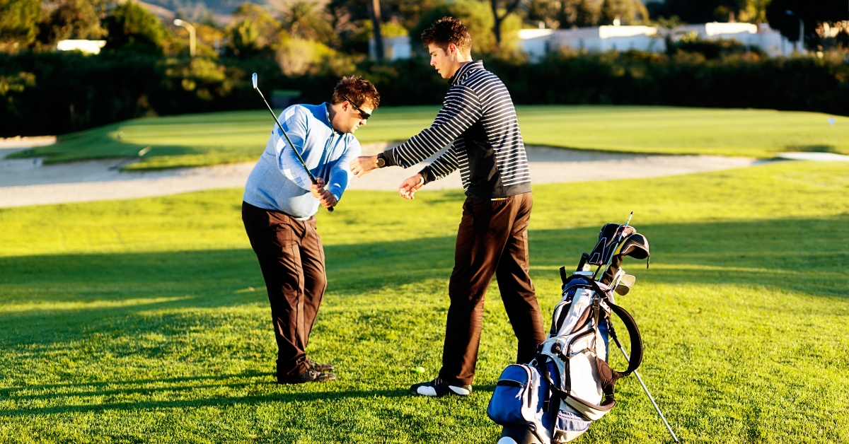 A coach correcting a golfer's swing